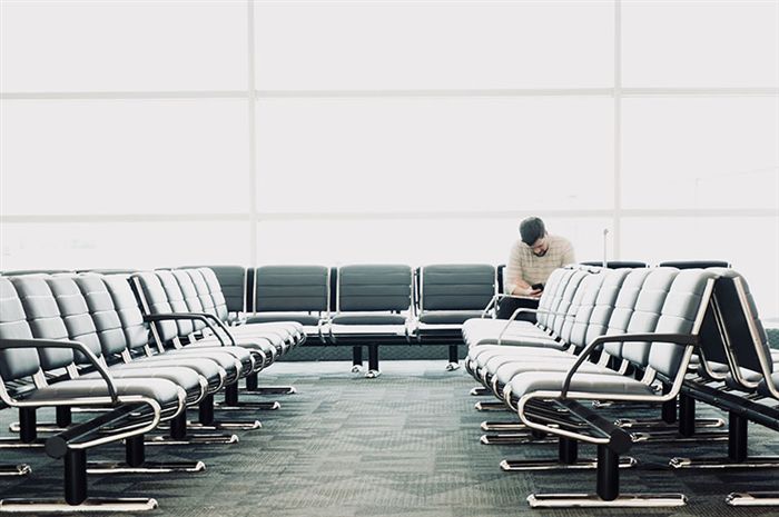 Человек, сидящий возле ворот в аэропорту