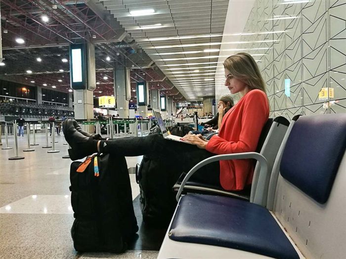 Женщина, путешествующая с ноутбуком, работает на ноутбуке в международном аэропорту Бразилии.
