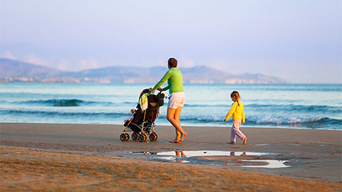 Женщины и дети на пляже на коляске.