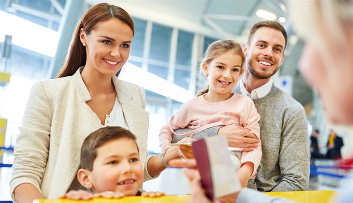 Веселая семья на стойке регистрации в терминале аэропорта