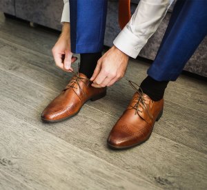 Мужчина, завязывающий шнурки на кожаных туфлях.
